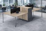 A modern 4-person office workstation featuring light oak wood desktops, slim metal legs, black privacy screens, and integrated slate grey vertical storage cabinets.